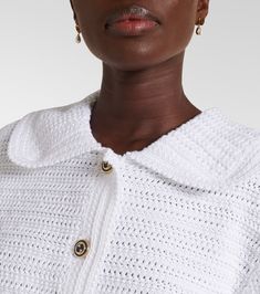 a woman wearing a white sweater and gold earrings