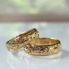 two gold wedding rings sitting next to each other on a white counter top with a window in the background