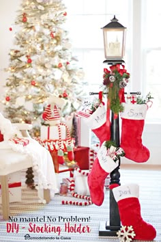 christmas stockings hanging from a lamp post in front of a decorated christmas tree with presents