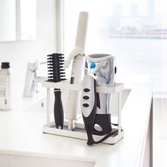 a hair dryer, combs and other items are on a counter in front of a window