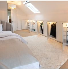 an attic bedroom with white walls and carpeted flooring, built in closets