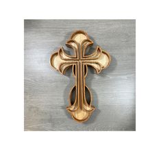 a wooden cross hanging on the side of a metal wall mounted plaque with wood accents