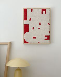 a white lamp sitting next to a red and white painting on a wall above a table