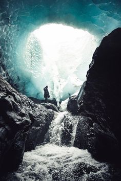 a man sitting in the middle of a cave with water coming out from inside it