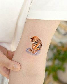 a small tiger tattoo on the left arm and right arm, with water running down it's side