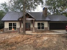 a house that is in the middle of some dirt and has a lot of trees around it