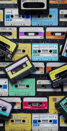 many cassette tapes are stacked on top of each other in different colors and sizes,