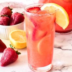 two glasses filled with watermelon lemonade next to strawberries and lemons