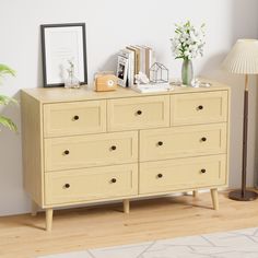 a dresser with many drawers and pictures on it next to a lamp in a room