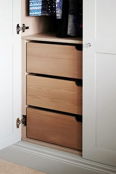 an open closet with drawers and clothes hanging on the doors