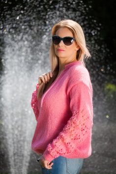 a woman wearing sunglasses standing in front of a fountain