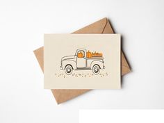 a card with an orange truck and pumpkins on the back, sitting on top of a brown envelope