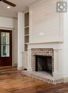 an empty living room with a fireplace and wooden floors