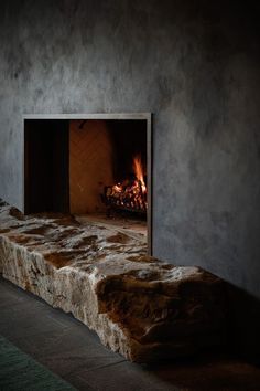 a stone bench with a fire in the fireplace