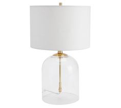 a clear glass table lamp with a gold metal base and a white shade on the top