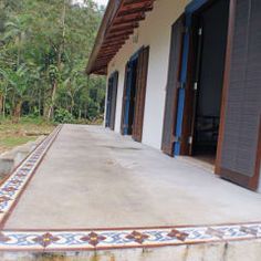 an outside view of a house with blue shutters and tile on the front porch