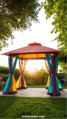 A vibrant gazebo with multicolored drapes stands in a garden, illuminated by the sunset. Gazebo Aesthetic