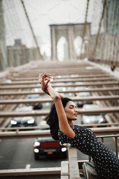 a woman standing in front of the brooklyn bridge with her hand up to her head