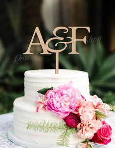 a white wedding cake with pink flowers and the initials as f on it's top