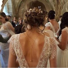 the back of a woman's wedding dress in a church with other people standing around