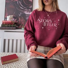 Storyteller Sweatshirt Writer Author Writing Literary Shirt Creative Writing English Major Screenwriter Poet Librarian Gift A sturdy and warm sweatshirt bound to keep you warm in the colder months. A pre-shrunk, classic fit sweater that's made with air-jet spun yarn for a soft feel and reduced pilling. * 50% cotton, 50% polyester * Pre-shrunk * Classic fit * 1x1 athletic rib knit collar with spandex * Air-jet spun yarn with a soft feel and reduced pilling * Double-needle stitched collar, shoulde Fall Magic, Literary Shirts, Teacher Cups, Become Smarter, Maroon Sweatshirt, Dark Academia Clothing, English Major, Nerd Shirts, Useful Gifts