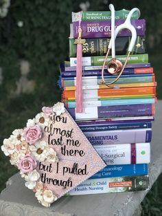 a stack of books with some flowers and a book bag sitting on top of it