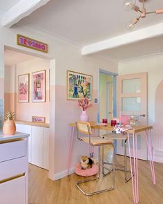 a pink and white room with a desk, chairs, and pictures on the wall