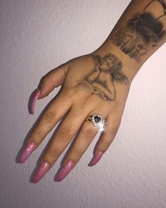 a woman's hand with tattoos on it and a ring in her left hand