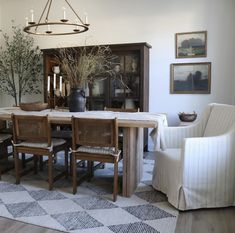 a dining room table with chairs and a potted plant in the center, on top of a checkered rug