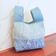 a blue and white bag sitting on top of a wooden floor next to a wall