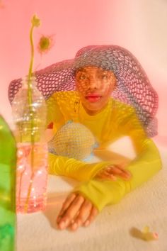 a woman sitting in front of a vase filled with flowers and holding a glass ball