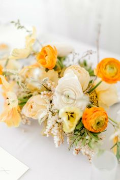 an arrangement of yellow and white flowers on a table