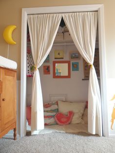 a bedroom with white curtains and pictures on the wall