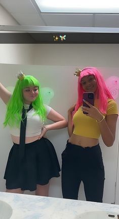 two women with green hair are taking a selfie in front of a bathroom mirror