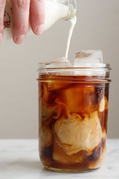 a person is pouring ice into a jar filled with liquid and food coloring on the inside