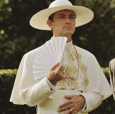 a man wearing a white hat and holding a fan