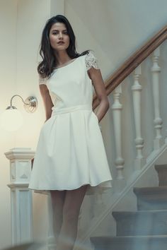 a woman in a white dress is standing on the stairs with her hands on her hips