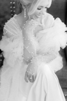 black and white photo of a woman in a dress sitting on a bench with pearls around her neck