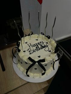 a birthday cake with white frosting and black decorations