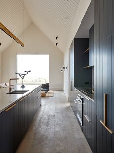 an open kitchen with black cabinets and counter tops, along with a large window that looks out onto the outdoors