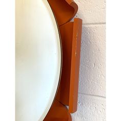 a round mirror mounted to the side of a white wall next to a brick wall