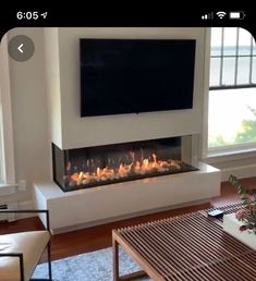 a living room with a large television mounted on the wall and a fire place in front of it