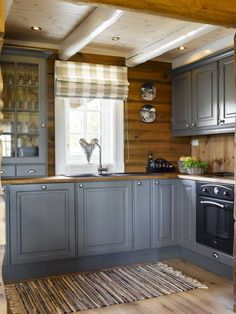 a kitchen with gray cabinets and wooden floors, along with an area rug on the floor