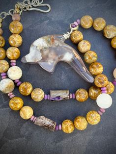 Offering is for this exact necklace measuring approx. 18 inch (slightly adjustable but average is 18 inches).  Featuring a polished carved flower agate dolphin, phosphosiderite rondelles, and AAA fossil coral polished round beads.  All metal is sterling silver.  Also there is a little charoite in the necklace as well.  Love the colors on this - gold and purple. Adjustable Carved Spiritual Necklace, Adjustable Carved Round Necklace, Adjustable Resin Beaded Necklace For Gift, Adjustable Round Carved Necklaces, Adjustable Carved Round Necklaces, Carved Agate Round Necklaces, Round Carved Agate Necklaces, Adjustable Round Agate Necklace, Adjustable Agate Necklace With Gemstone Beads