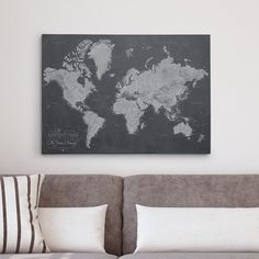 a large black and white world map mounted on the wall above a couch with pillows