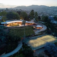 an aerial view of a tennis court surrounded by greenery and trees at night time