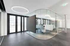 an office with glass walls and white furniture