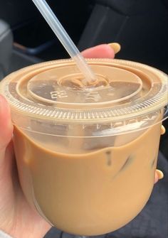 a person holding a plastic cup with a straw in it