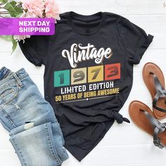 a t - shirt with the words vintage on it next to some jeans and sandals