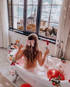 a woman sitting in a bathtub with balloons floating around